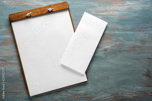 Clipboard with empty sheets of paper on wooden table