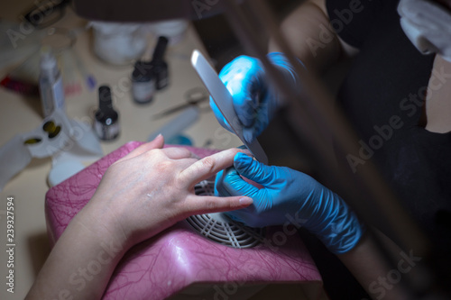 The girl on the manicure. The master covers the nail gel polish. Cosmetic procedures..