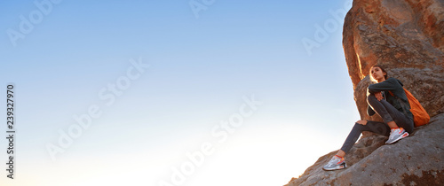 woman is standing on the cliff against background of sunrise © vitaliymateha