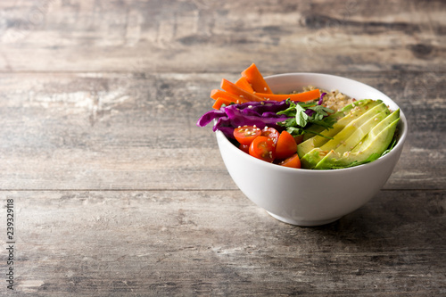 Vegan Buddha bowl with fresh raw vegetables and quinoa on wooden table. Copyspace
