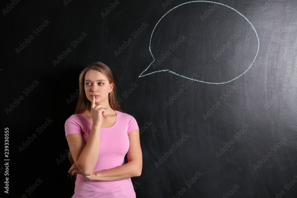 Thoughtful young woman and blank speech bubble drawn on blackboard