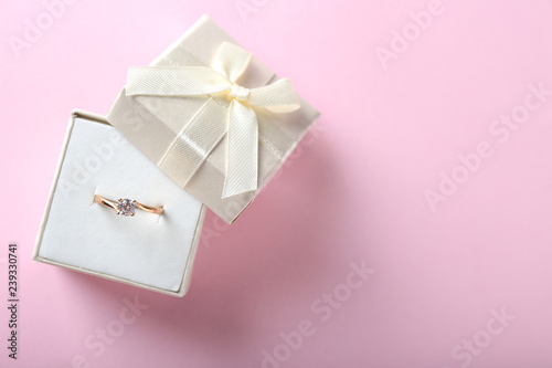 Box with beautiful engagement ring on color background