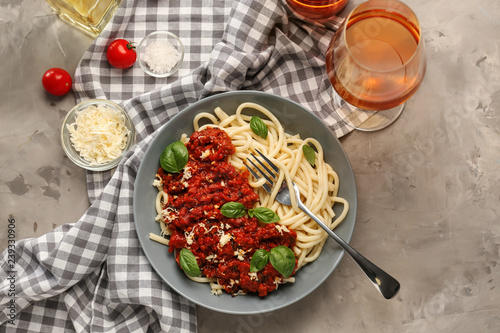 Plate with delicious pasta bolognese and wine on grey table