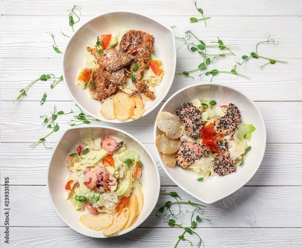 Plates with different tasty salads on white wooden table Plates with different tasty salads on white wooden table