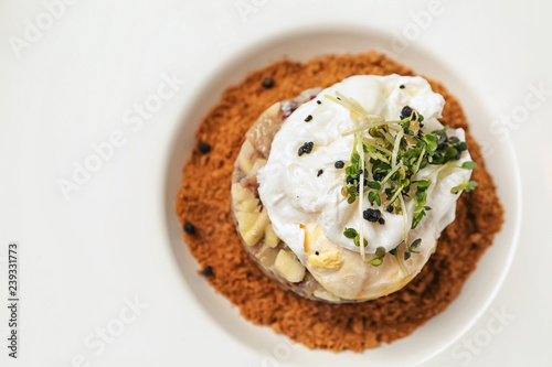 Herring tartar with poached egg on plate, closeup
