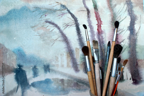 Watercolor paint brushes against aquarelle background