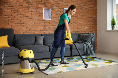 Female janitor hoovering ca...
