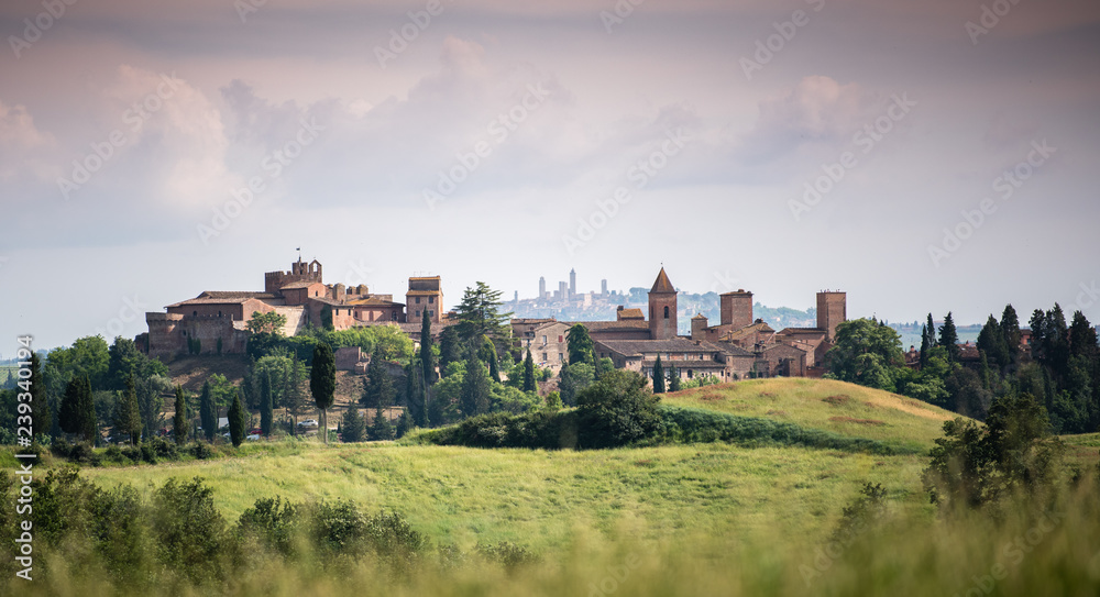 Scenic panorama of medieval village of Certaldo old town, Italy, with San Gimignano towers in the background, typical Italian and Tuscany countryside landscape