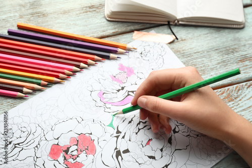 Woman coloring anti-stress picture at table