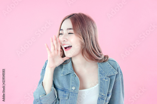 Asian woman whisper about secret to good health, blue jean clothing, pink background