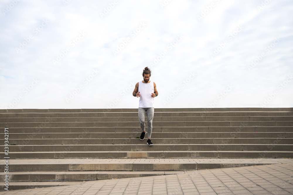 young man with long hair wearing sport wear going up and down  the stairs