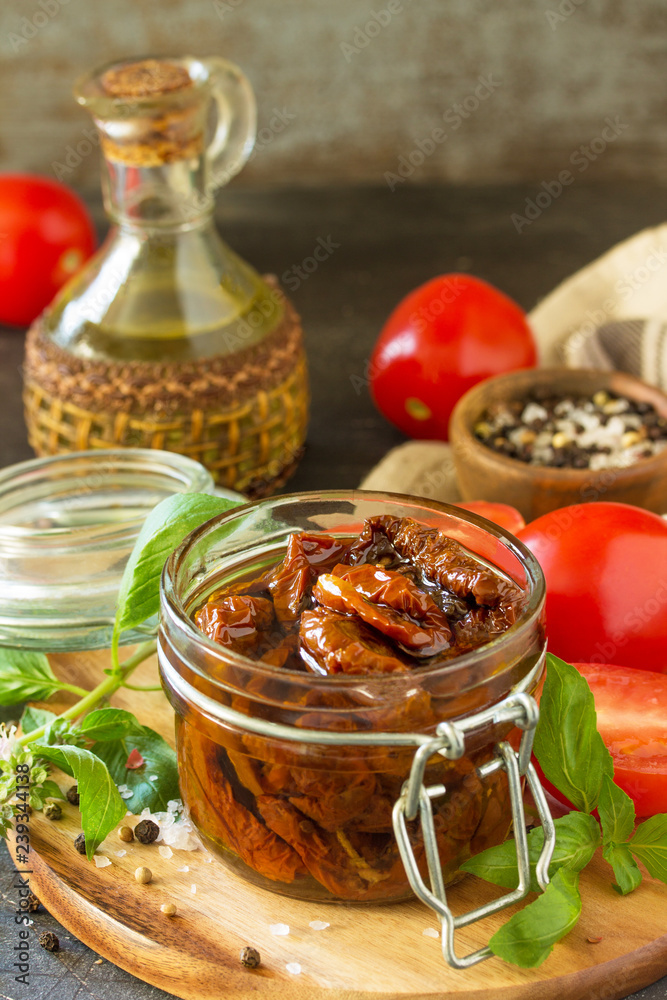 Sun dried tomatoes with olive oil in a jar on black stone or concrete table. Copy space. Sun dried tomatoes with olive oil in a jar on black stone or concrete table. Copy space.
