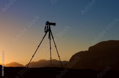 Camera on a tripod isolated in sunrise background. silhouette of camera on tripod with mountains background in sunrise, camera prepared to take photos, tripod. shooting mountains in sunrise or sunset