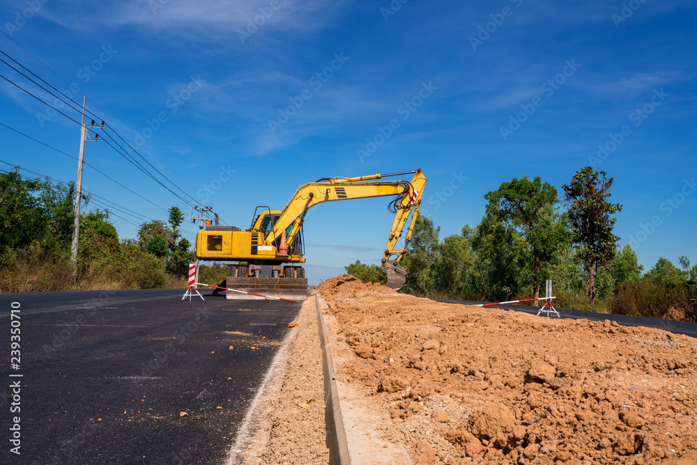 Industrial backhoe dig the ground in road construction Industrial backhoe dig the ground in road construction