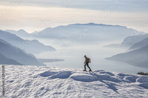 Winter view of Lake Como while a hiker proceeds with snowshoes Vercana mountains High Lario Lombardy Italy Europe photo
