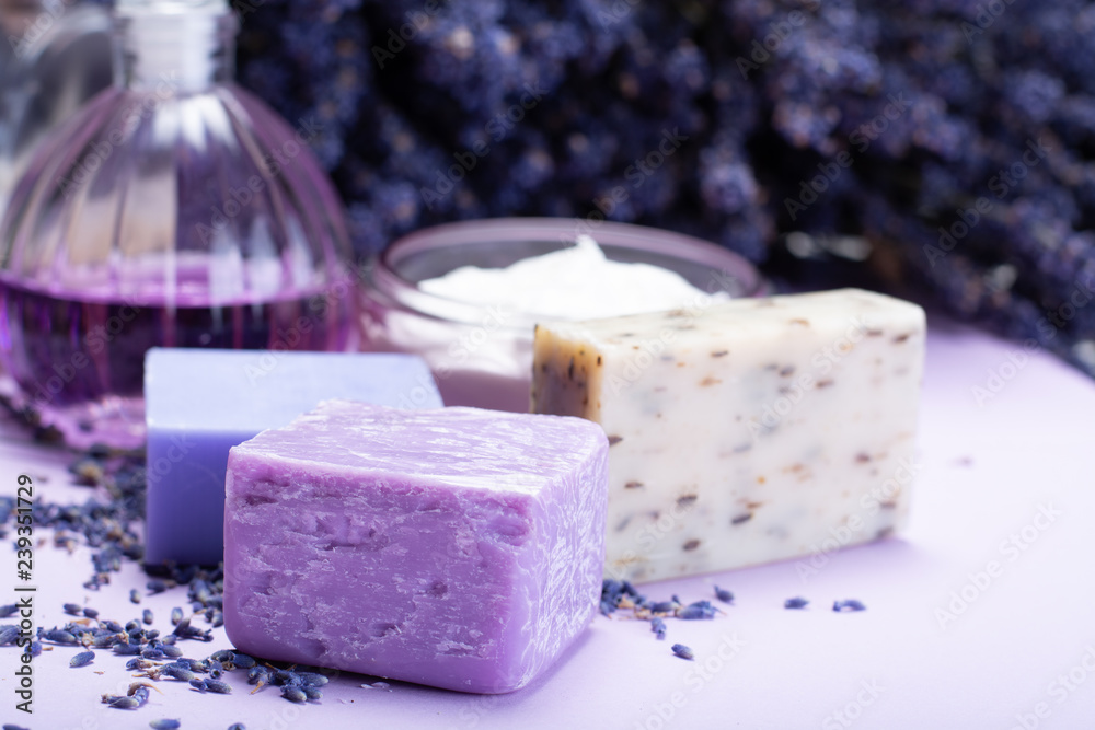 Natural healthy aromatherapy and skin treatment with organic French lavender, lavender soap, face cream, essential oils on purple background with dried lavender flowers