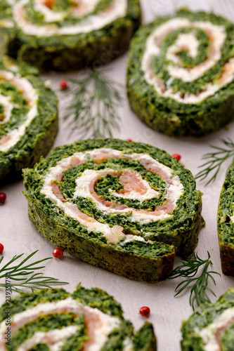 Spinach roulade stuffed with cream cheese and smoked salmon sliced on a white background, close-up.  Delicious appetizer, party food