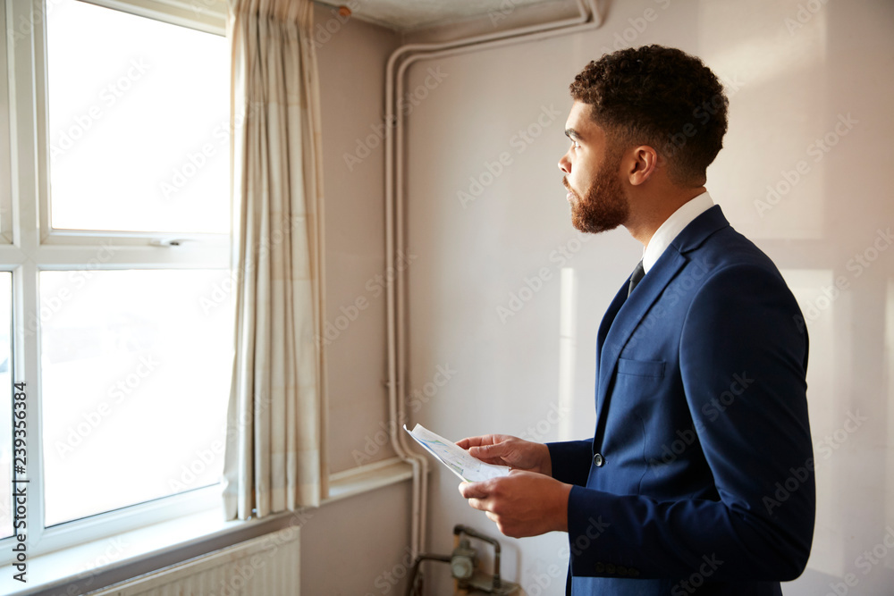 Male Realtor Looking At House Details In Property For Renovation Male Realtor Looking At House Details In Property For Renovation
