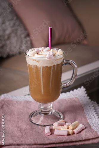 Glass cup of tasty frappe coffee with marshmallow on table