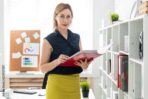 A young girl standing in the office and holding a folder with documents. photo