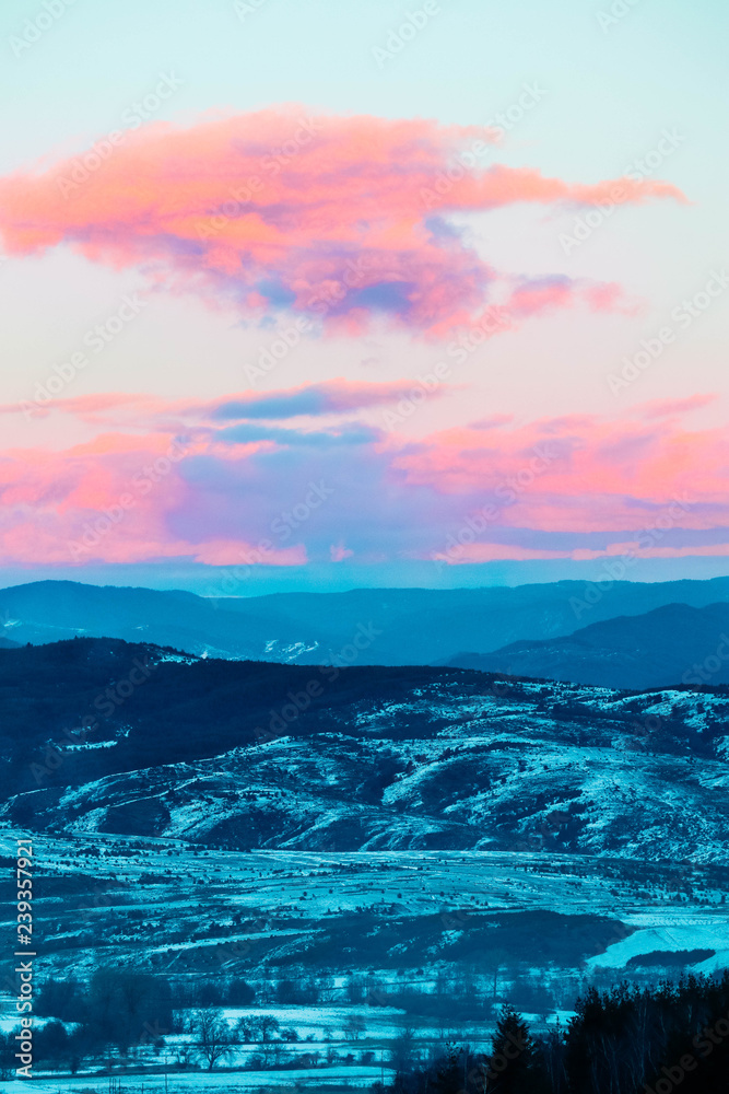 Colorful sunset in hills, pink clouds. Provence fields landscape covered with snow, sunset purple light.