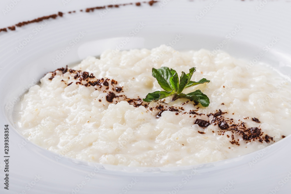 Rice porridge with grated chocolate in plate over grey background. Healthy breakfast ingredients. Clean eating, vegan food concept Rice porridge with grated chocolate in plate over grey background. Healthy breakfast ingredients. Clean eating, vegan food concept
