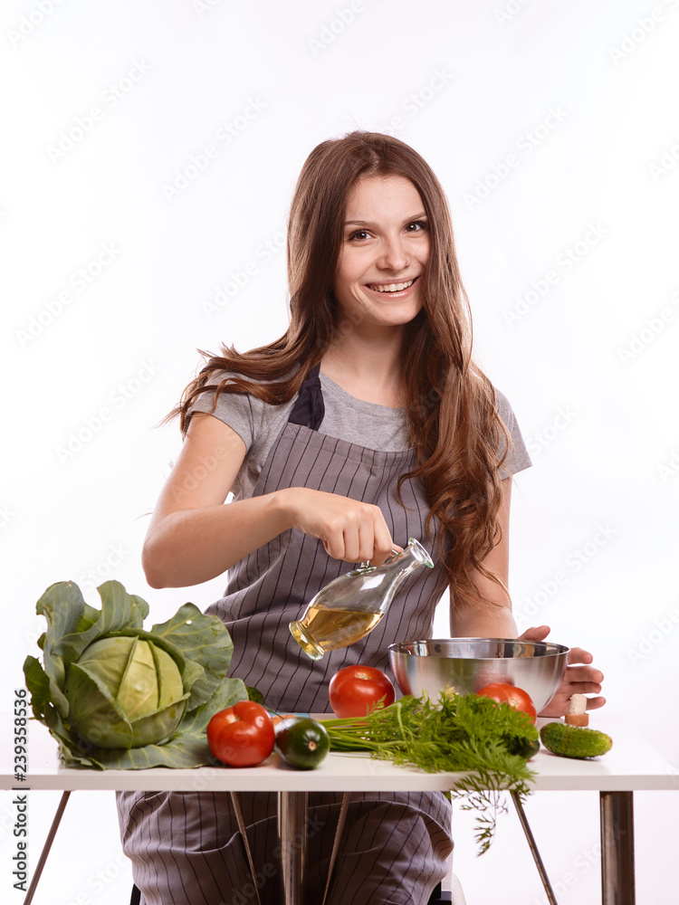 happy adult woman with various fresh vegetables on kitchen table looking at camera