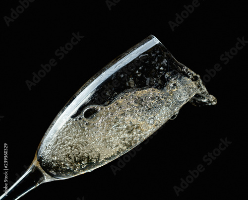 Glass of splashing champagne isolated on black. © Igor Normann