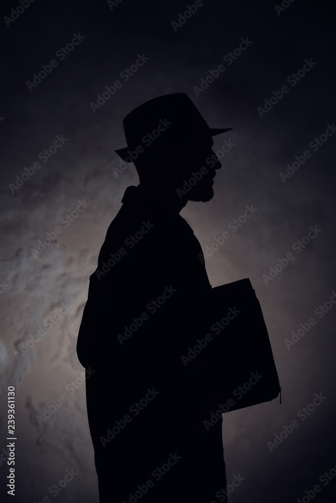 Silhouette of detective on dark background
