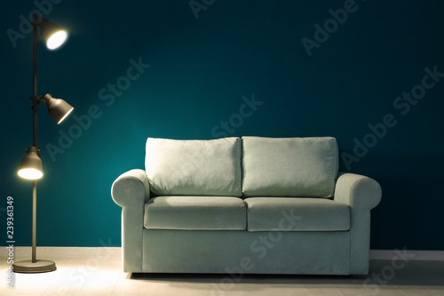 Comfortable sofa and lamp near color wall in room © Pixel-Shot