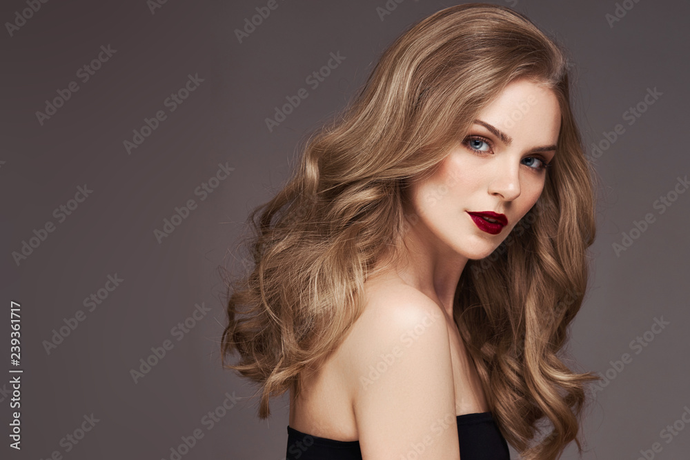 Naklejka premium Blonde woman with curly beautiful hair smiling on gray background.