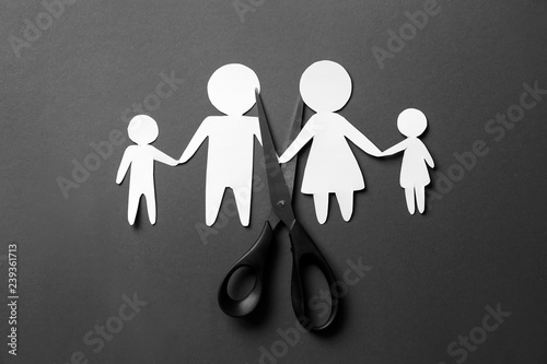 Scissors with paper figures of family on dark background. Concept of divorce photo