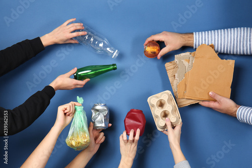 Many hands with different types of garbage on color background. Ecology concept photo