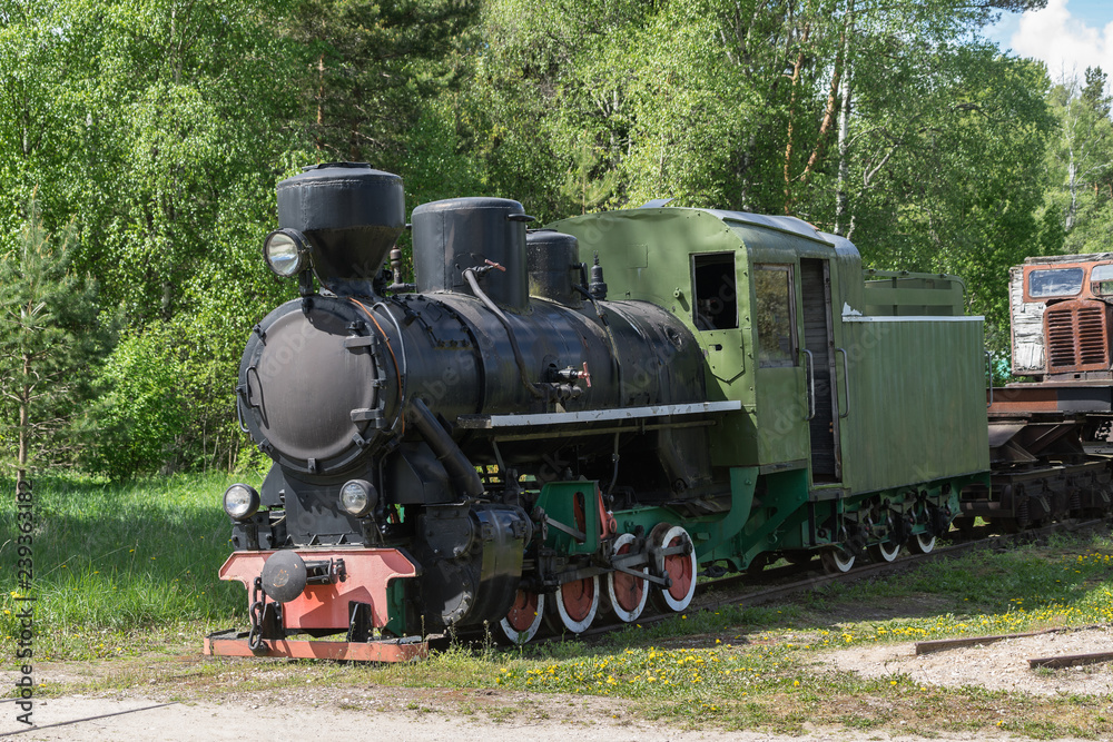 Old train and locomotive. Railroad tracks stretches and green grass and trees. Railway road environment background. Old train and locomotive. Railroad tracks stretches and green grass and trees. Railway road environment background.