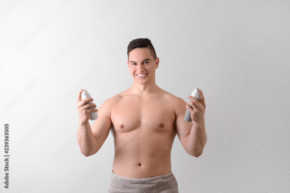 Fototapeta premium Young man with deodorants on light background