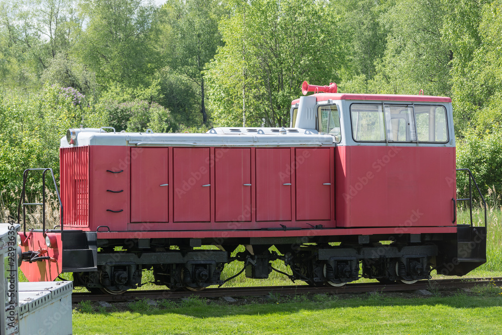 Naklejka premium Old train and locomotive. Railroad tracks stretches and green grass and trees. Railway road environment background.