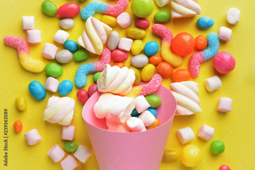 Tasty sweets and paper cone on color background, closeup Tasty sweets and paper cone on color background, closeup