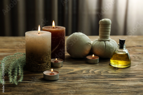 Beautiful spa composition with burning candles, essential oil and herbal bags on wooden table