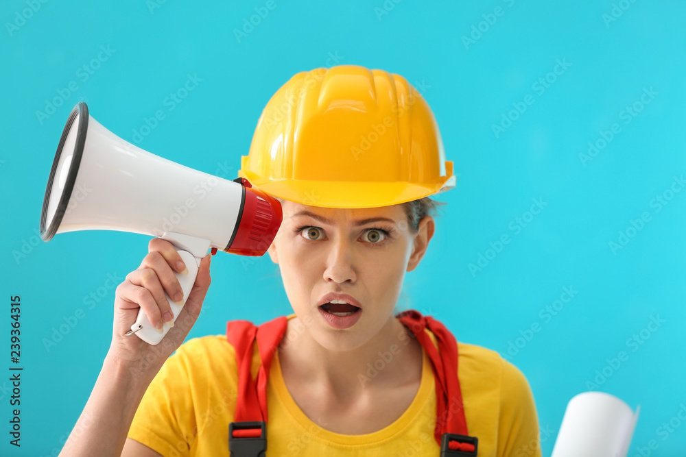 Shocked female engineer with megaphone on color background Shocked female engineer with megaphone on color background
