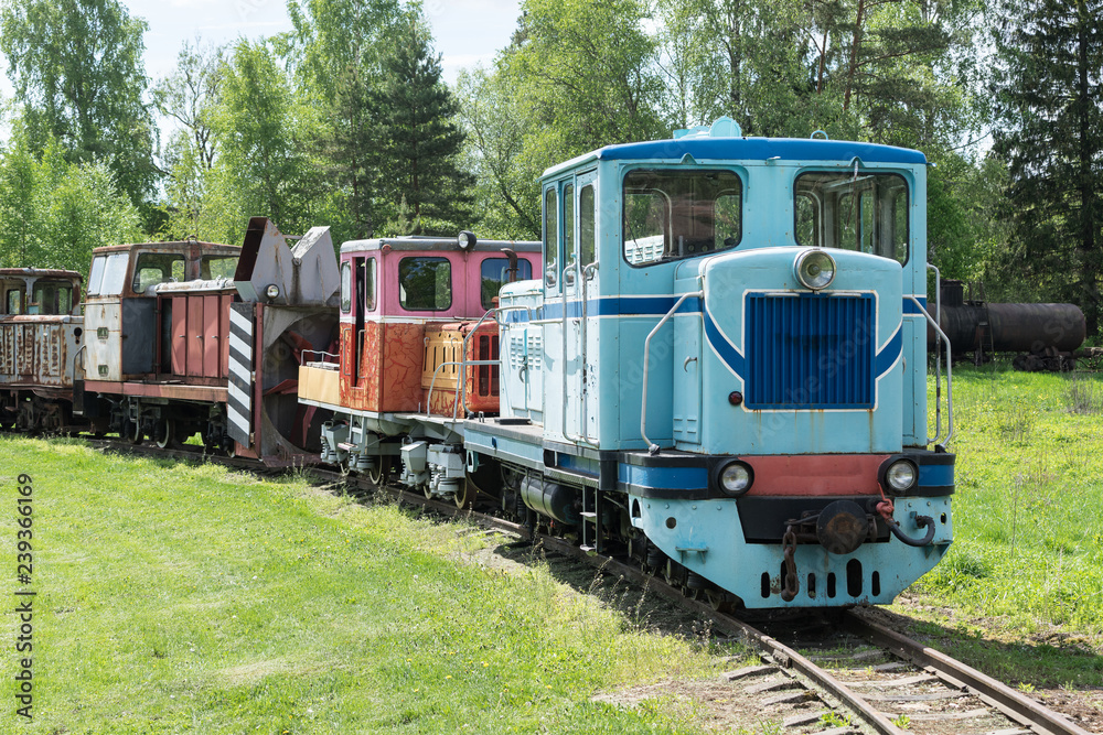 Old train and locomotive. Railroad tracks stretches and green grass and trees. Railway road environment background. Old train and locomotive. Railroad tracks stretches and green grass and trees. Railway road environment background.