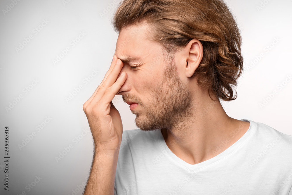 Young man suffering from headache on light background Young man suffering from headache on light background