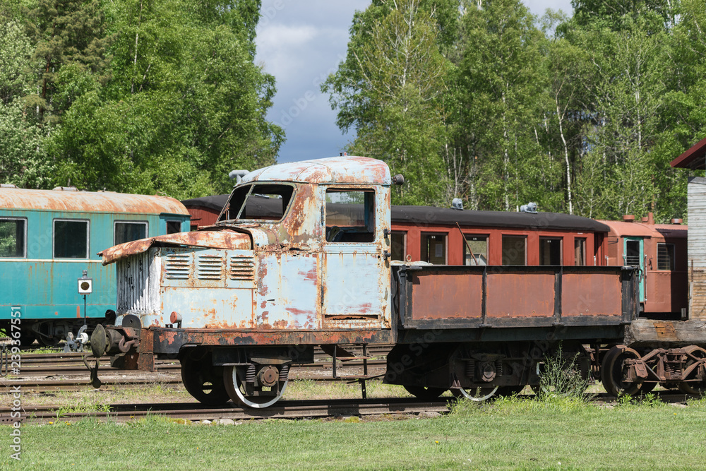 Old train and locomotive. Railroad tracks stretches and green grass and trees. Railway road environment background.