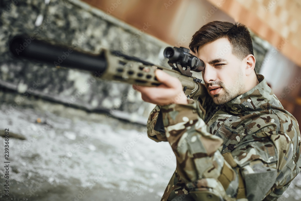 A military soldier targets and holds a large rifle in the building A military soldier targets and holds a large rifle in the building