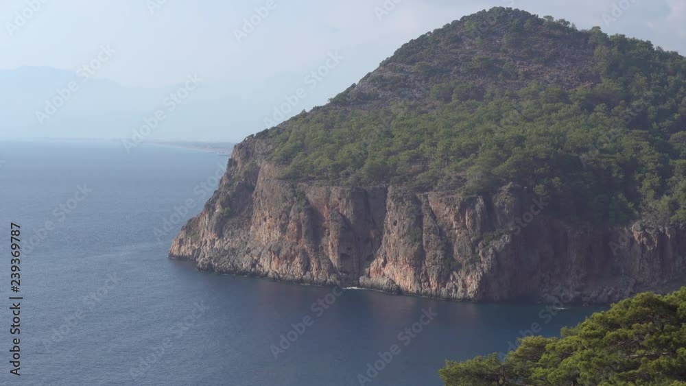 Rocky Antalya coast of the Mediterranean Sea on a summer sunny day. Natural landscape with a coastline with green coniferous trees Rocky Antalya coast of the Mediterranean Sea on a summer sunny day. Natural landscape with a coastline with green coniferous trees