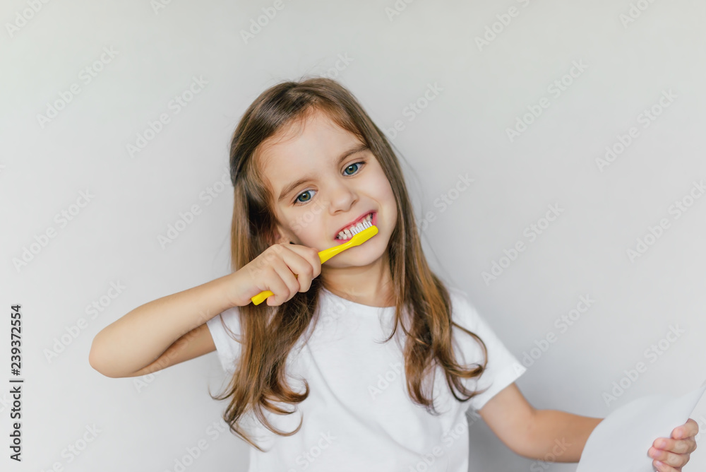 Little cute baby girl with toothbrush and tooth layout in hand. The concept of health, oral hygiene, people and beauty. The layout of the space. Selective focus. Little cute baby girl with toothbrush and tooth layout in hand. The concept of health, oral hygiene, people and beauty. The layout of the space. Selective focus.