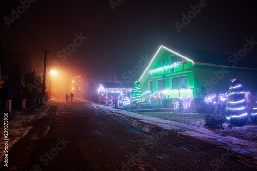 Couple walking together on the street in christmas evening. Christmas lights on the houses