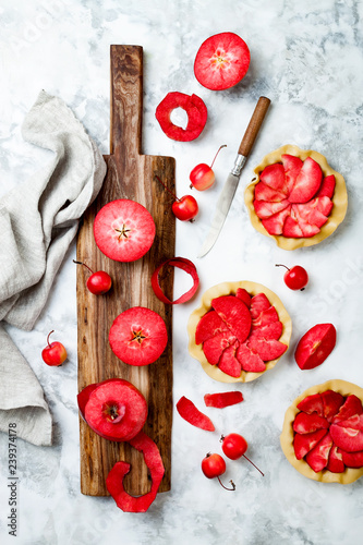 Baking apples pies over white marble table, top view. Cooking mini tarts with fresh red apples Baya Marisa. photo