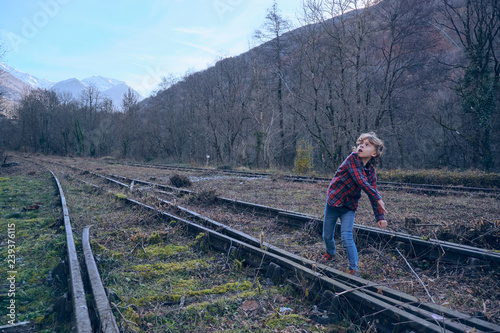 Boy with rock on old railways near hills photo