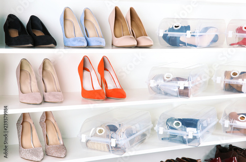 Footwear and plastic boxes on shelves in wardrobe. Shoe storage organization