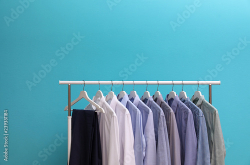 Wardrobe rack with men's clothes on color background. Space for text